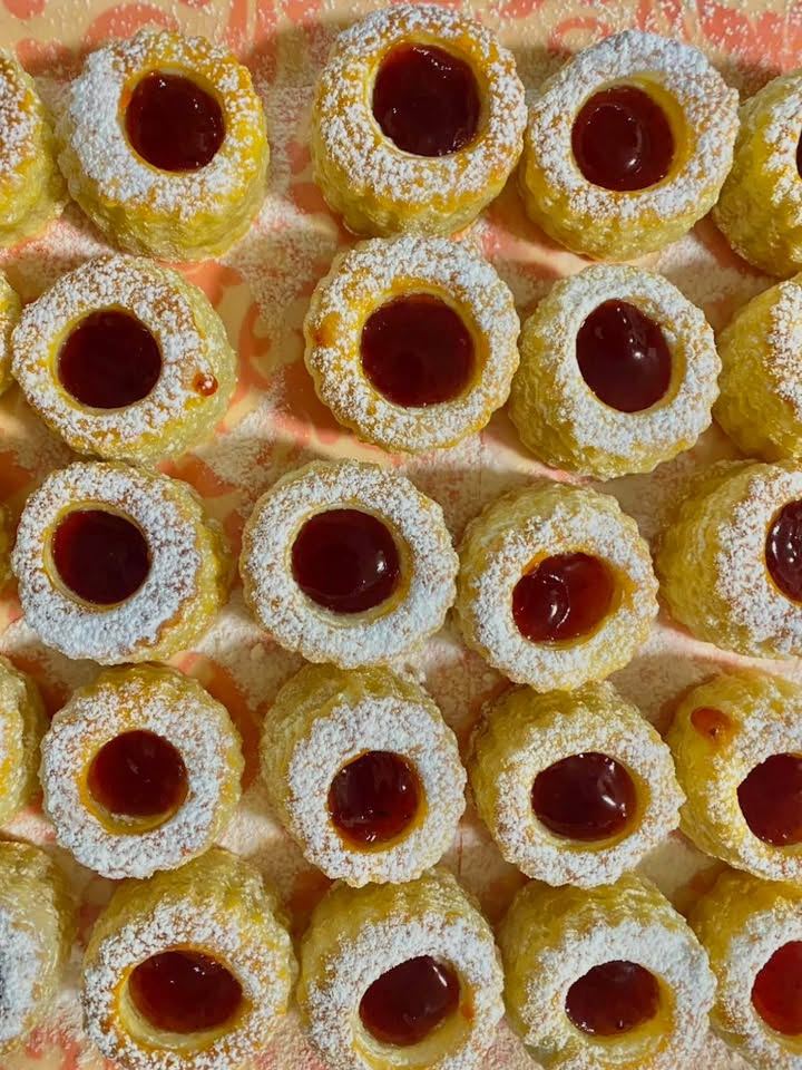 Rows of coconut jam tarts with glossy red jam centres